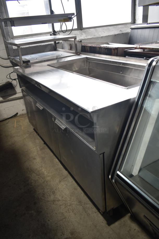 Commercial stainless steel prep station on casters, dual shelves, and under-counter storage. Good condition.
