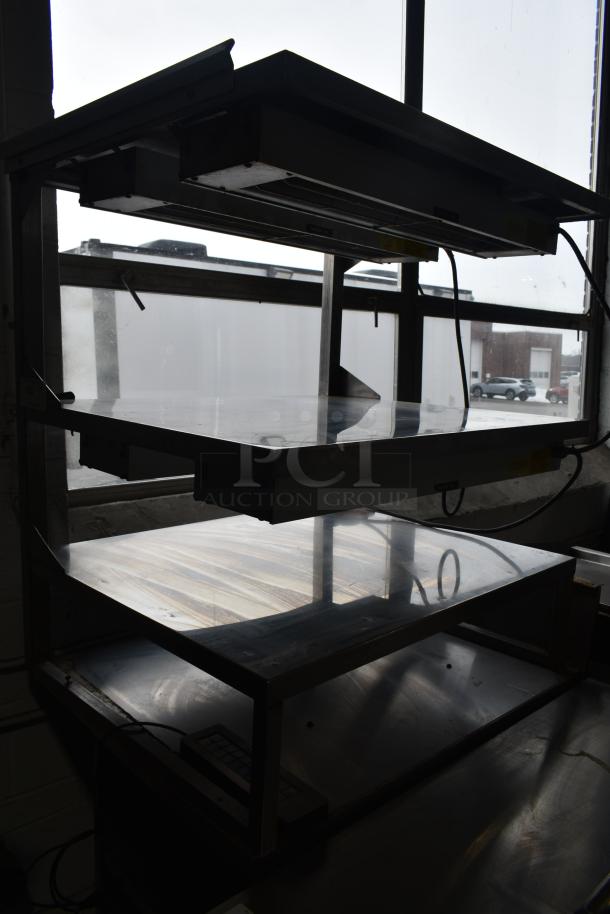 Commercial multi-shelf merchandiser display with warming strips, featuring three metal shelves, visible wiring, and stainless steel finish, in used condition.