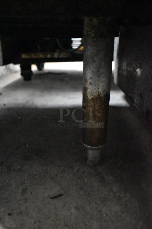 Commercial multi-shelf merchandiser display with warming strips; visible rust on metal leg, indicating wear and use.