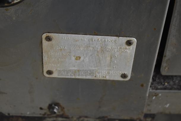 Bakers Pride commercial gas pizza oven label showing clearance requirements, slightly worn but legible.