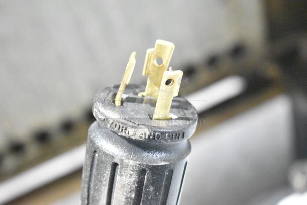 Close-up of a three-pronged plug for the Unox Cadco XAFT183-US convection oven, showing label details.
