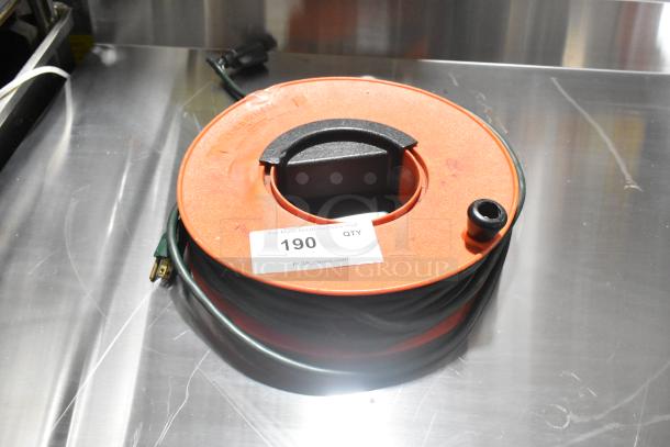 Orange extension cord reel with black handle, coiled green cord, and visible label "190" from PCI Auctions.