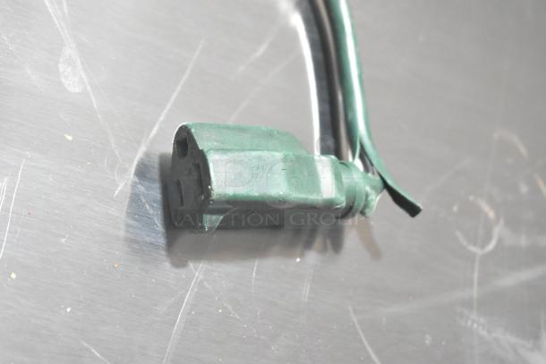 Extension cord with green plug on reel, showing light wear.