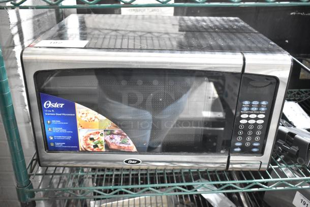 2020 Oster OGJ41302 Countertop Microwave Oven, stainless steel, 120V, 1.3 cu. ft., keypads visible, excellent condition.
