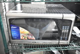 2020 Oster OGJ41302 Countertop Microwave Oven, stainless steel, 120V, 1.3 cu. ft., keypads visible, excellent condition.
