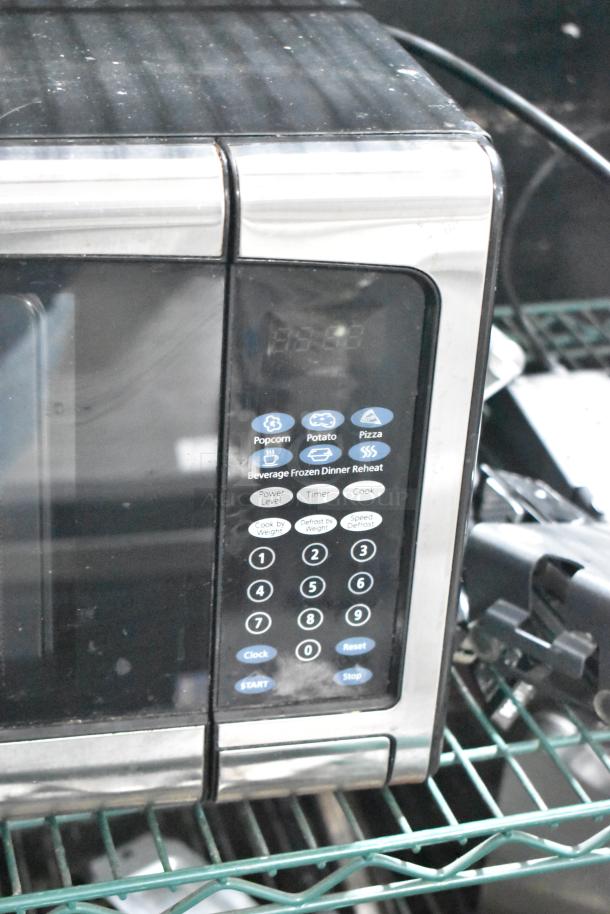 2020 Oster OGJ41302 countertop microwave oven. Black with stainless steel accents, keypad with preset options, 120V, 1 phase.