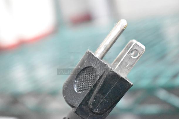 Close-up of a black two-prong plug of the 2020 Oster OGJ41302 countertop microwave oven.