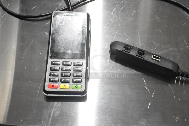 Verifone card reader P400 on metal surface, visible scratches, connected adapter with ports.