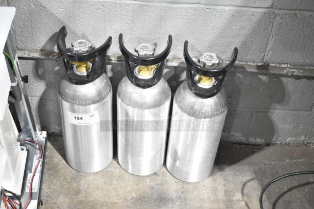 Three silver CO2 tanks with black valves, each labeled "194" indicating quantity of three. Buyer pick-up required.