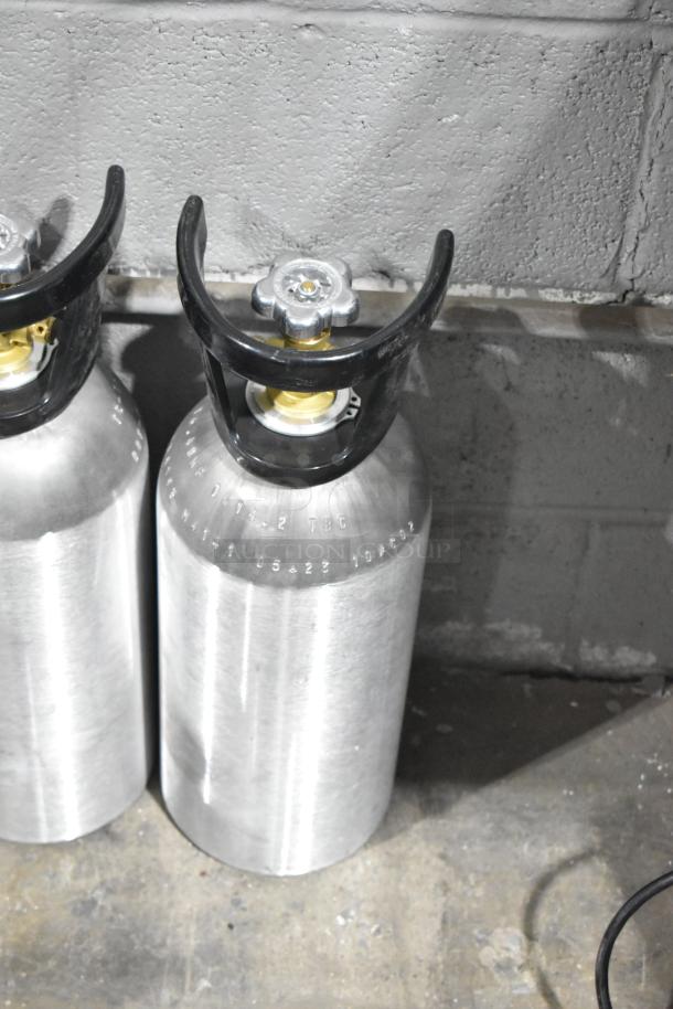 Three CO2 tanks with black handles and visible embossed markings, in good condition, for pickup only.
