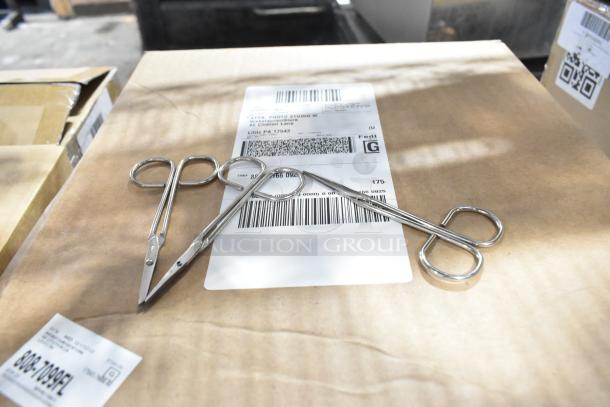 Cardboard box with shipping label, containing 9 new scratch and dent boxes including medical supplies. Scissors on top.