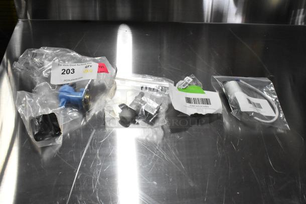 Four brand new items including a capacitor and inlet valve, each in packaging with visible tags and labels, some noted as scratch and dent.