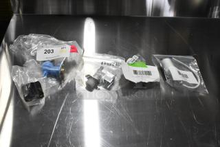 Four brand new items including a capacitor and inlet valve, each in packaging with visible tags and labels, some noted as scratch and dent.