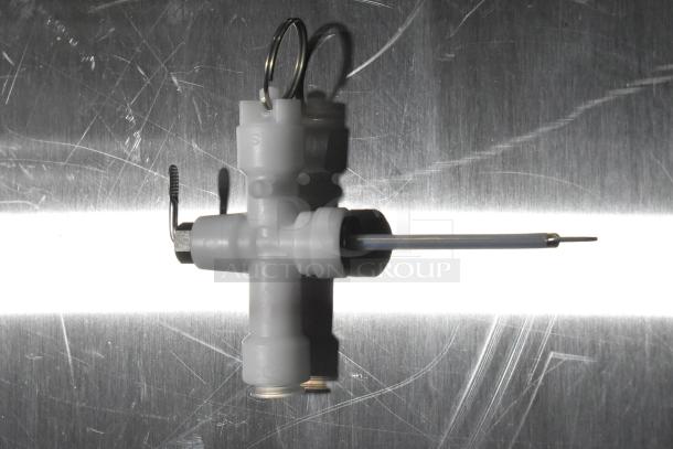 Plastic inlet valve with metal fittings, new condition, set on a scratched metallic surface.