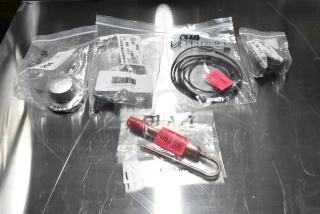 Five new scratch and dent items, including a hinge, probe, and knob, in sealed bags with visible labels and barcodes.