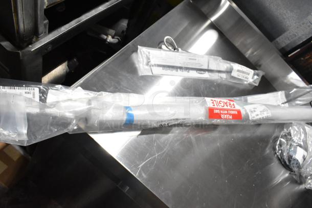 Four brand new heating elements, labeled as fragile, wrapped in plastic on a metal surface. Scratch and dent condition.