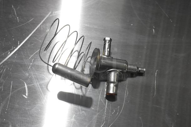 Brand new expansion valve, metallic finish, with coiled sensor. Minor surface scratches visible.