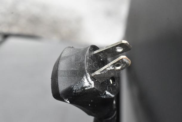 Close-up image of a standard two-prong black power plug with signs of wear and slight oxidation.