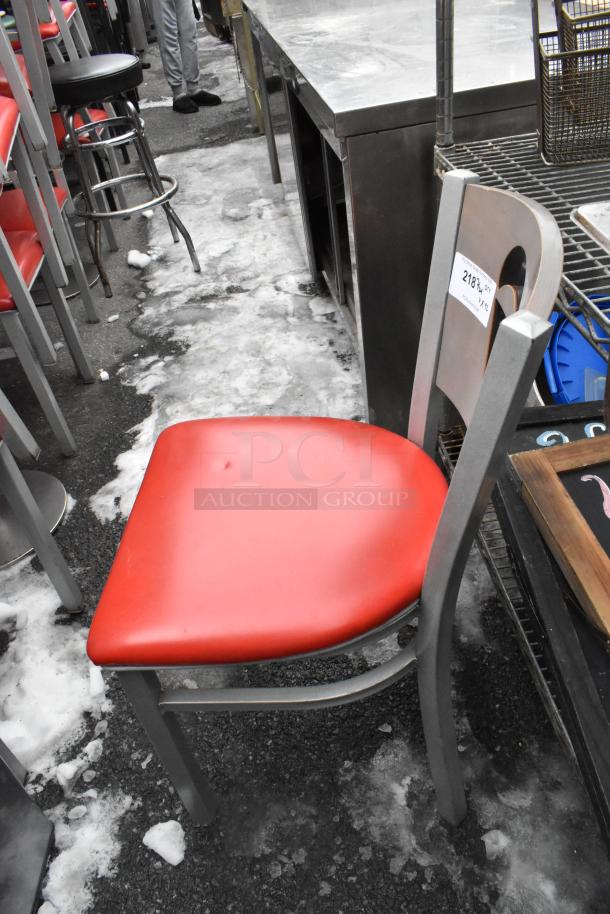 Metal dining height chair with red seat cushion, gray frame. Seat auction label reads "218." Good condition.