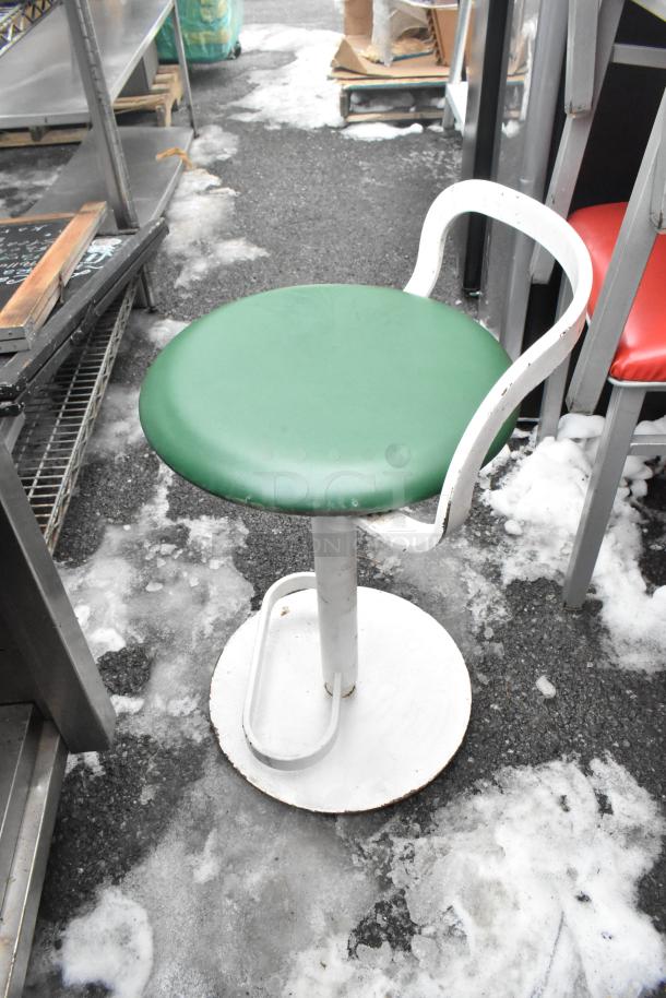 Metal stool with a green cushion and white frame, part of a set of 46 dining chairs. Red cushion chairs visible. Used condition.