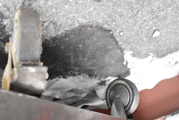 Commercial table caster and undershelf view; includes a sturdy metal frame and wheels for mobility. Condition shows wear.