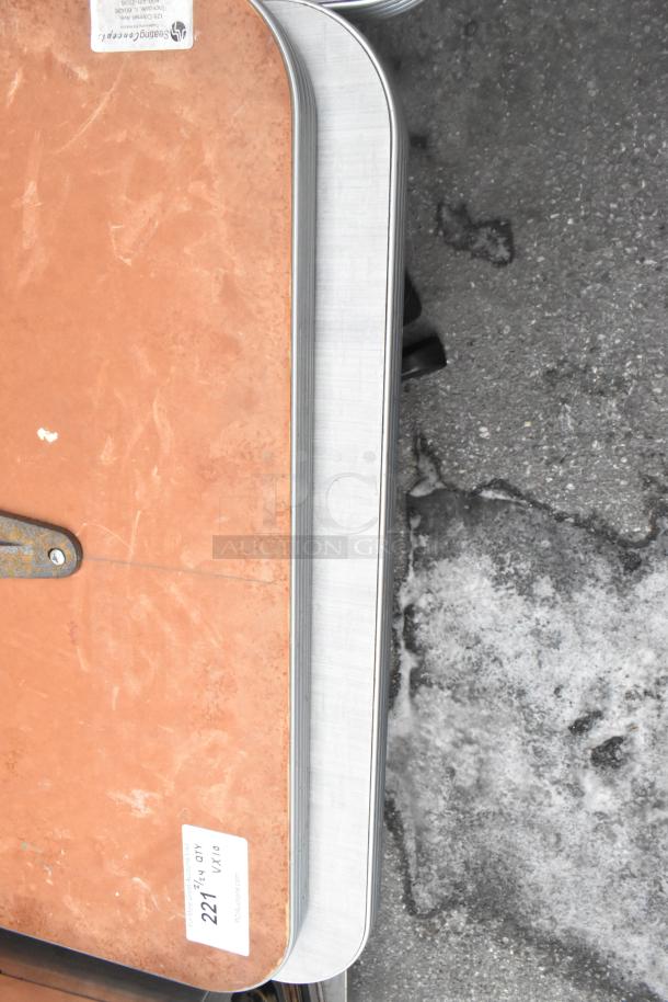 Set of 10 dining tables with brown tops and black metal bases. Tables show moderate wear. Auction label: "221 x10".