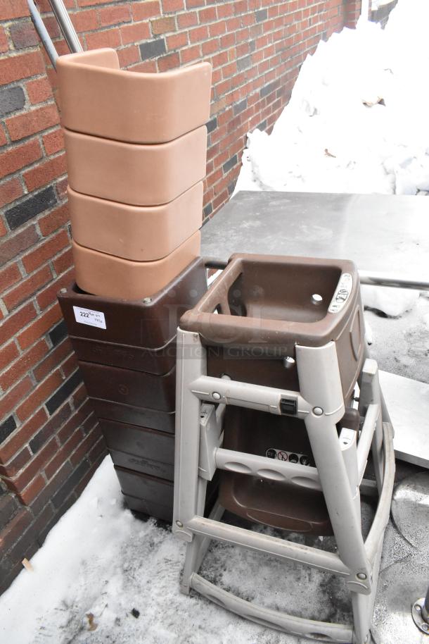 Stack of 8 brown booster seats and 2 high chairs against a brick wall. Good condition. Auction tag reads "Lot 222".