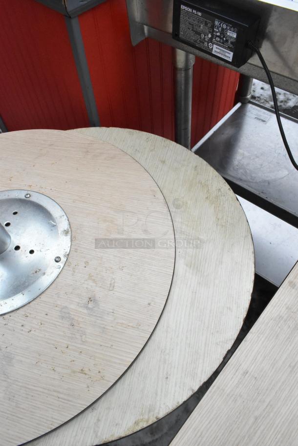 Four circular tables with wooden tops and metallic bases, showing wear and minor stains, auction for 4 times your bid.