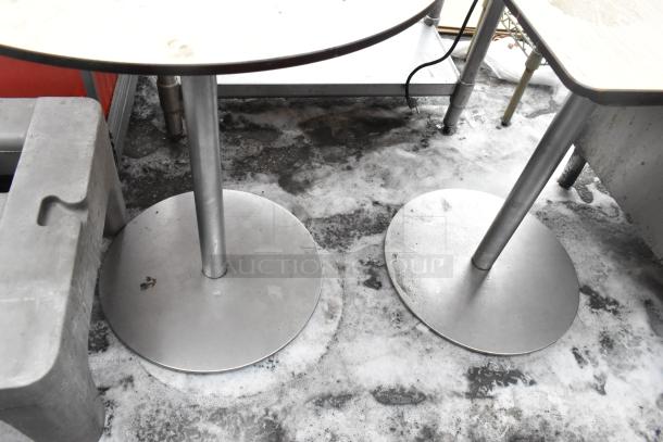 Four metal tables with round and square tops, industrial base, used condition, visible wear, suitable for commercial use.