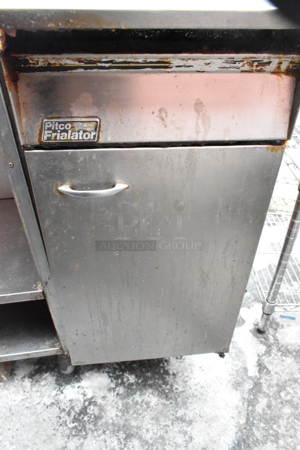 Pitco Frialator commercial gas fryer with two metal baskets. Stainless steel exterior, visible wear and use.