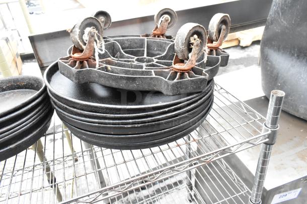 Chrome finish 3-tier wire shelving unit, includes stack of black pans and caster wheels on top, buyer must dismantle.