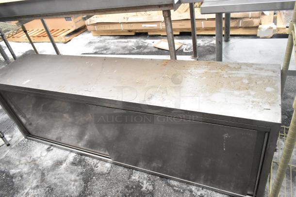 Stainless steel 2 door cabinet with visible surface wear and a sliding door. Industrial design, suitable for storage.