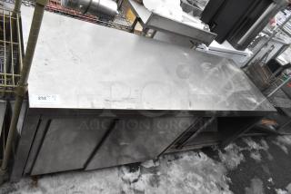 Stainless steel counter with two doors, under shelf, and signs of wear. Auction label "232" visible.