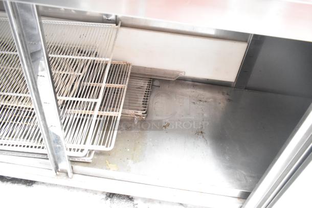 Stainless steel counter with two doors and under shelf, featuring wire racks. Some visible wear and stains, ideal for storage.