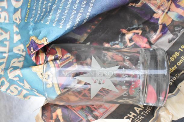 Regency 600TSB3036S table with a transparent "Hop Star Craft and Specialty Beer" glass placed on it, wrapped in colorful paper.