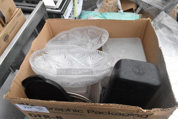 Pallet lot with clear decorative bowls, black poly bins, and metal table base posts in a cardboard box.