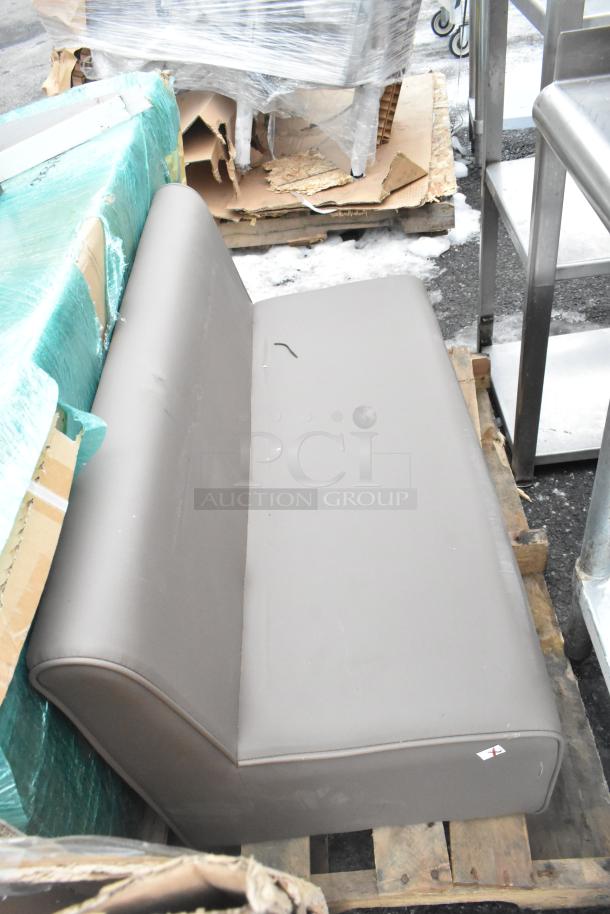 Pallet with assorted items including a brown cushioned seat, metal shelves, and wrapped stacks. Mixed condition.