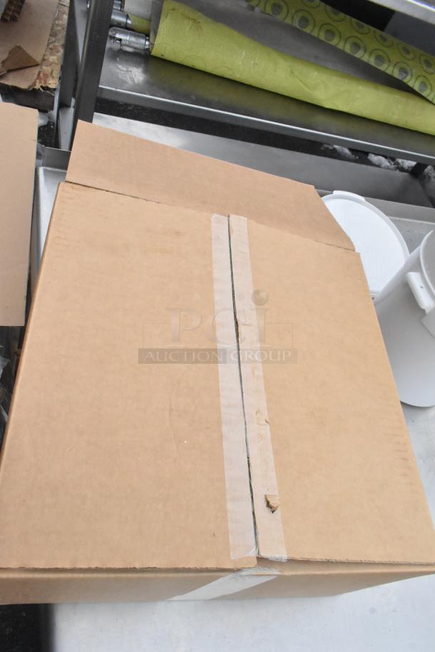 Pallet lot of various items including shelves and bins. Visible is a closed cardboard box on a metal surface.