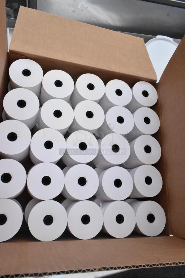 Cardboard box filled with white paper rolls, each featuring a black core, within a mixed pallet lot.