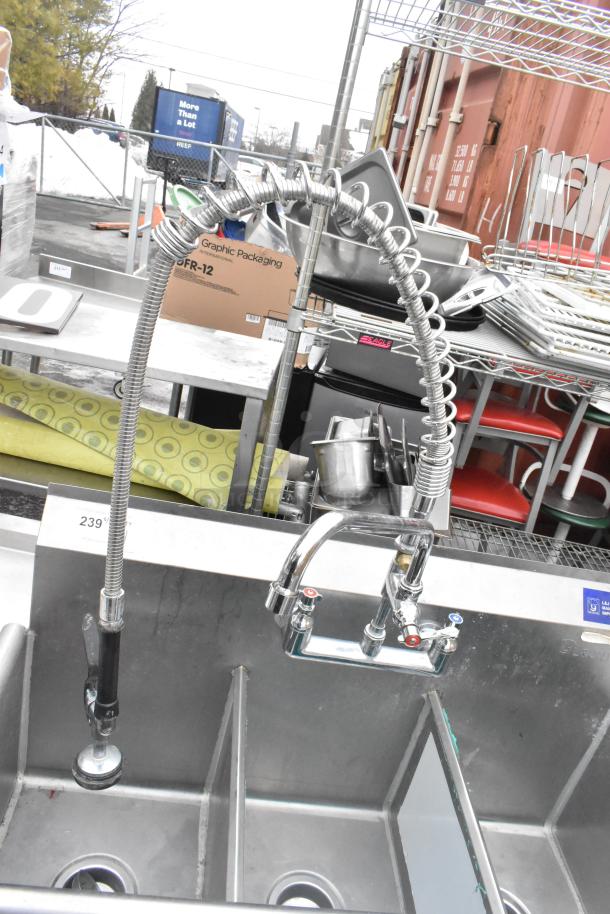 Commercial 3-bay sink with faucet, handles, and spray nozzle attachment. Stainless steel, pre-owned, minor wear visible.