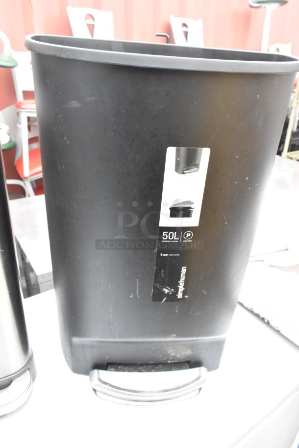 Black 50L trash can with a simplehuman label, featuring a pedal. Chrome finish can partially visible. Good condition.
