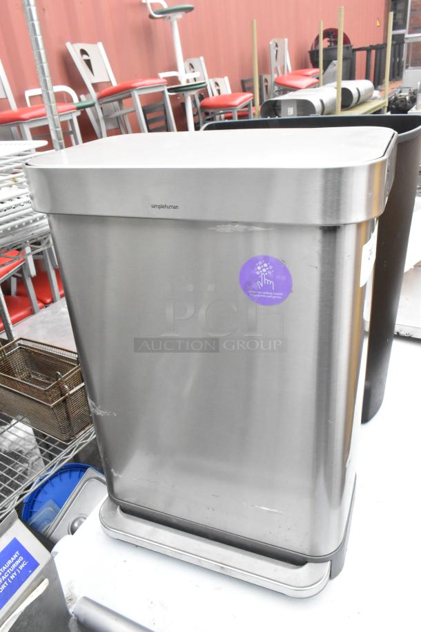 Black poly and chrome finish trash cans by Simplehuman. Visible labels and markings; good condition. Auction includes two.