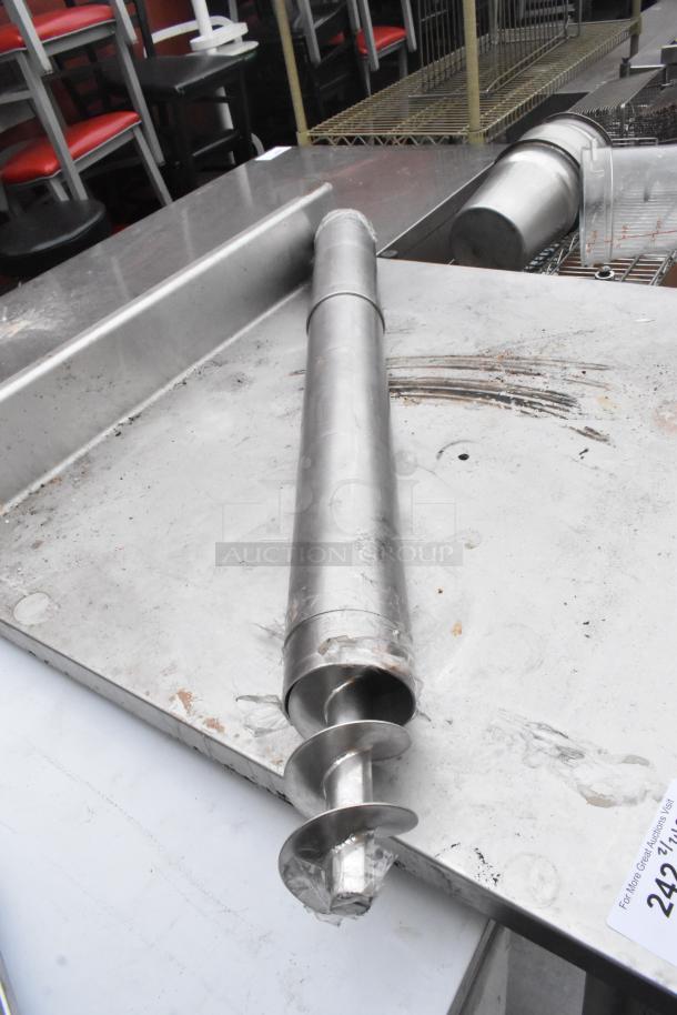 Stainless steel table with backsplash and under shelf, showing wear. Tag indicates item number 242; no visible brand.