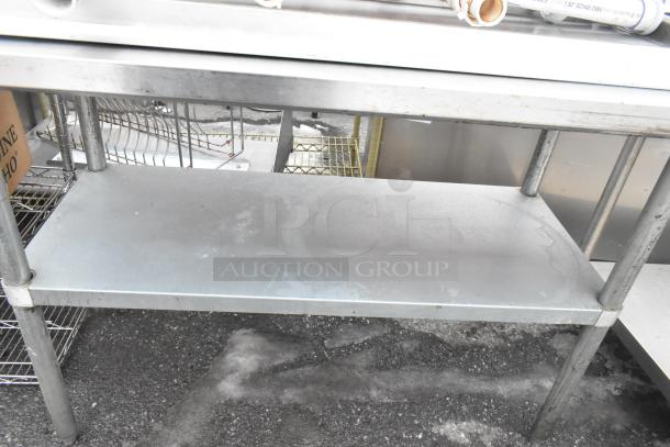 Two stainless steel tables with under shelves, industrial-grade, pre-owned, minor surface wear, ideal for storage or workspace.