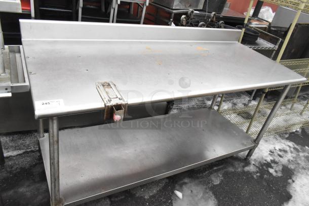 Commercial stainless steel table with backsplash, under shelf, and can opener mount. Good condition with minor surface wear.