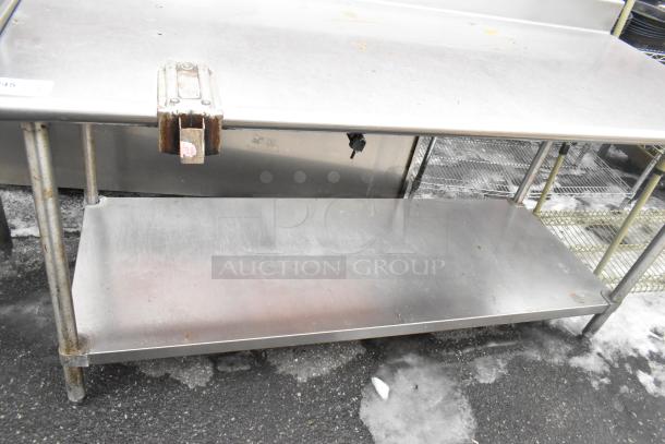 Commercial stainless steel table with backsplash, under shelf, and mounted can opener. Some surface wear visible.