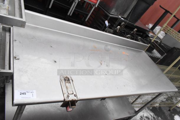 Stainless steel commercial table with can opener mount, backsplash, and under shelf. Shows wear and stains. Tag: "245".