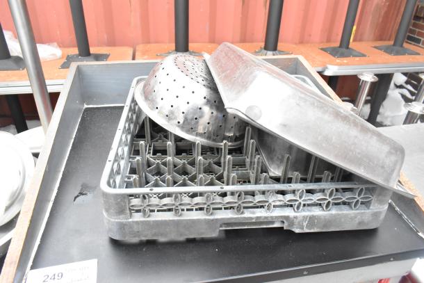 Metal counter with contents including a perforated colander and stainless steel pan, stored on a gray dish rack. Condition appears used.