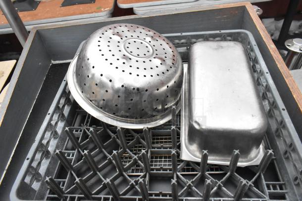 Metal colander and pan on a wooden counter with storage crate. Both are in used condition, ideal for kitchen use or display.