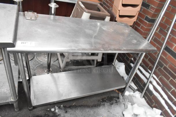 Commercial table with under shelf, sturdy metal construction, can opener mount, signs of wear, 25" wide, ideal for kitchens.
